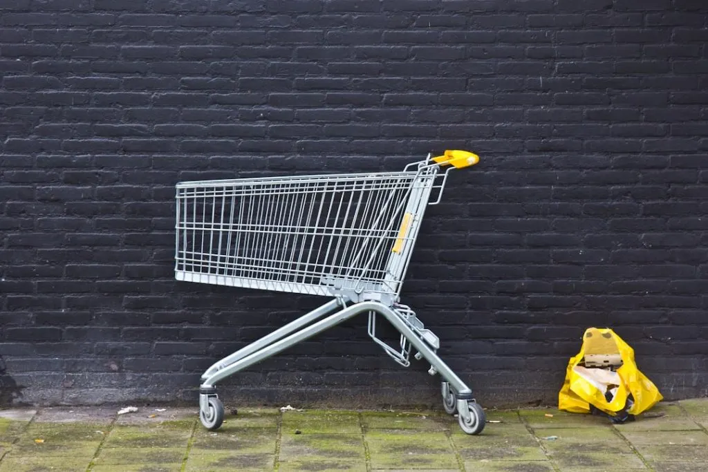A shopping cart sitting next to a brick wall