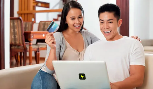 Person sitting with lady doing some work on laptop & lady holding credit card in hand